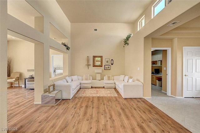 living room featuring a towering ceiling and light wood-type flooring