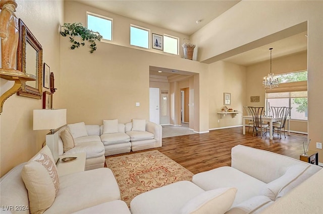 living room with hardwood / wood-style floors, a towering ceiling, and an inviting chandelier