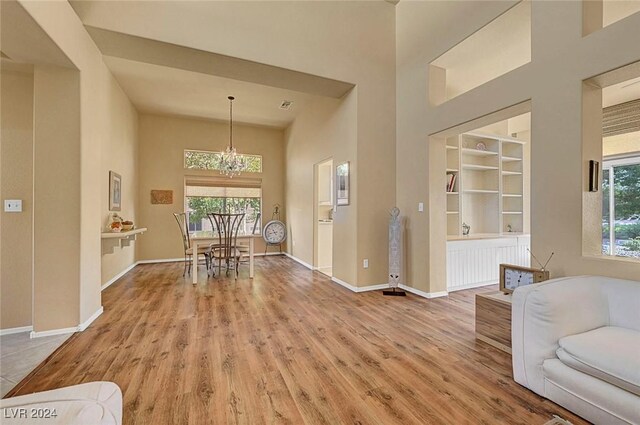 dining space with hardwood / wood-style floors, built in features, a high ceiling, and a chandelier