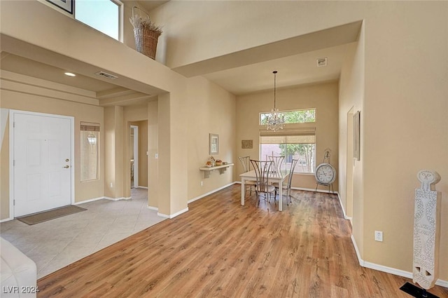 entrance foyer featuring a towering ceiling, light hardwood / wood-style flooring, and a notable chandelier