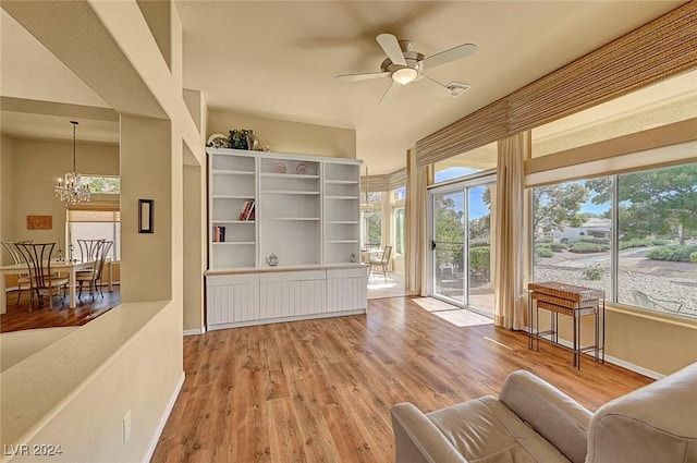 sitting room featuring ceiling fan with notable chandelier and wood-type flooring