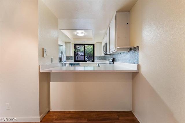 kitchen with stainless steel appliances, white cabinetry, backsplash, dark hardwood / wood-style flooring, and kitchen peninsula