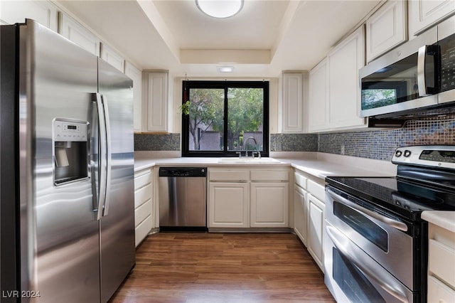 kitchen featuring stainless steel appliances, white cabinetry, sink, dark hardwood / wood-style floors, and backsplash