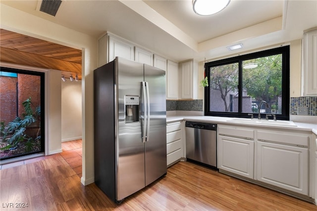 kitchen featuring stainless steel appliances, white cabinetry, and backsplash