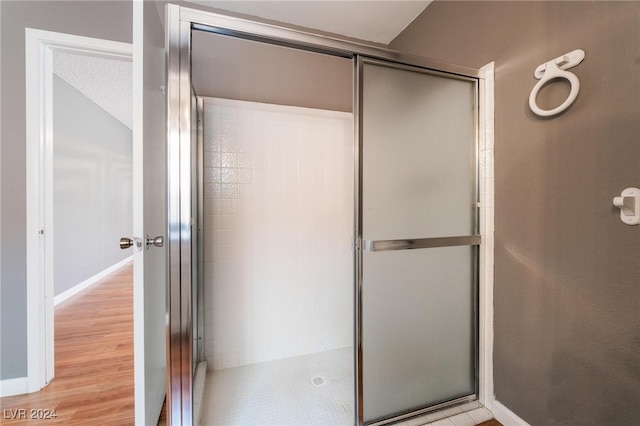 bathroom with wood-type flooring and a shower with door