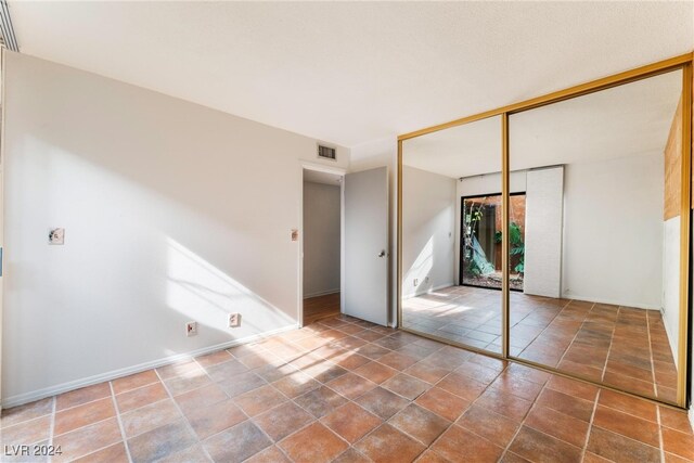 unfurnished bedroom with tile patterned floors and a closet