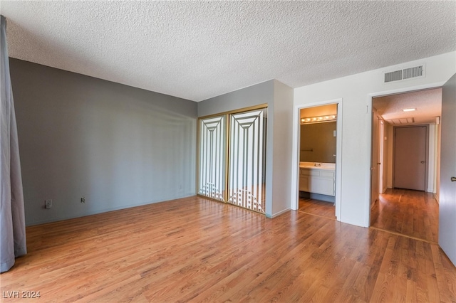 unfurnished room with a textured ceiling and light hardwood / wood-style flooring