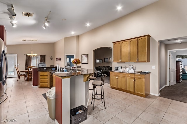 kitchen featuring an island with sink, light tile patterned flooring, pendant lighting, and high vaulted ceiling