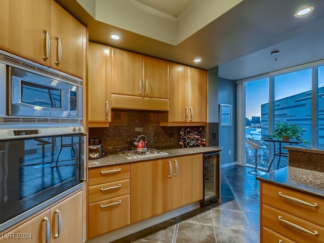 kitchen with beverage cooler, backsplash, stone countertops, and stainless steel appliances