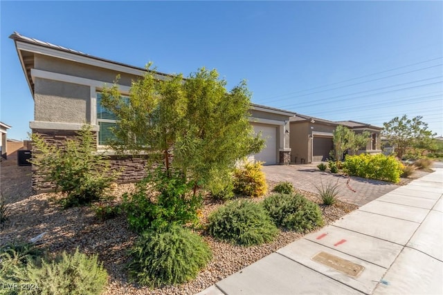 10254 Baronia St, Las Vegas, NV 89141 - view of property hidden behind natural elements featuring driveway, an attached garage, and stucco siding