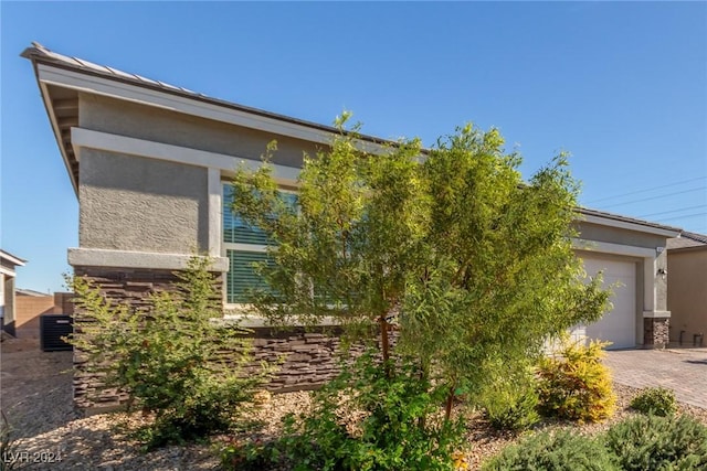 10254 Baronia St, Las Vegas, NV 89141 - view of side of property featuring driveway, stucco siding, a garage, and stone siding