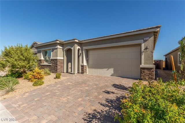 10254 Baronia St, Las Vegas, NV 89141 - view of front facade featuring stucco siding, stone siding, decorative driveway, and a garage