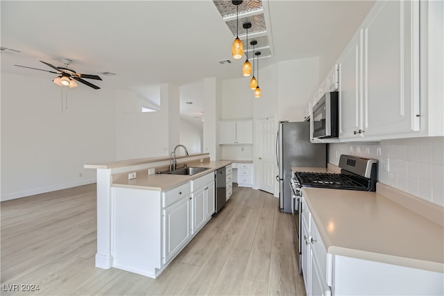 kitchen with stainless steel appliances, a center island with sink, hanging light fixtures, sink, and white cabinetry