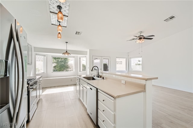 kitchen featuring stainless steel appliances, white cabinetry, sink, an island with sink, and light hardwood / wood-style flooring