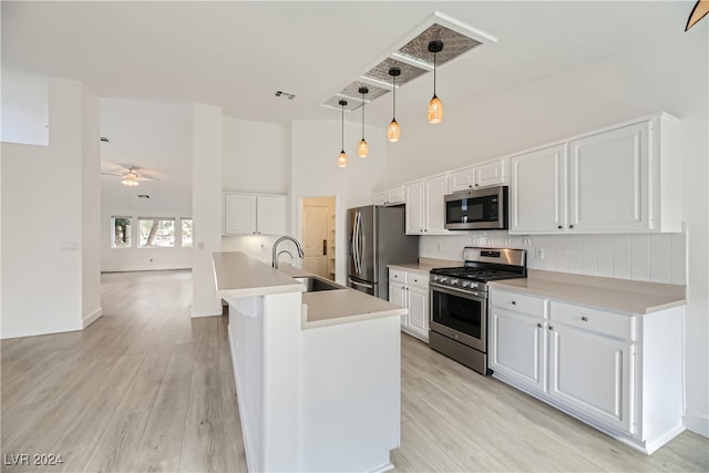 kitchen with light hardwood / wood-style flooring, sink, white cabinetry, appliances with stainless steel finishes, and decorative light fixtures