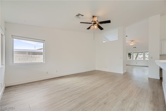 spare room featuring light hardwood / wood-style flooring, lofted ceiling, a healthy amount of sunlight, and ceiling fan