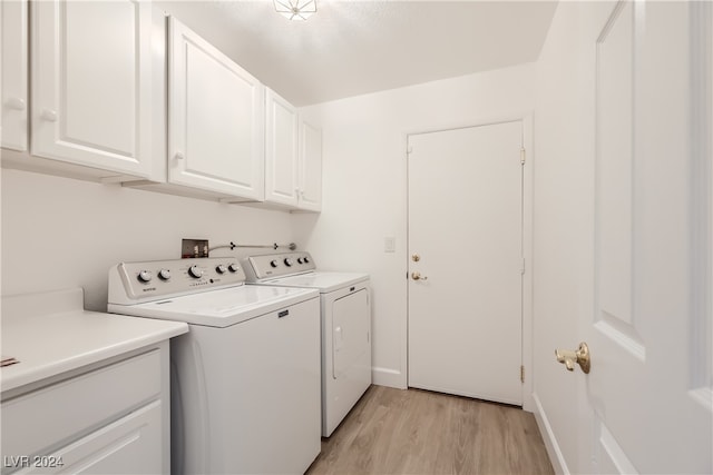 clothes washing area featuring light wood-type flooring, cabinets, and independent washer and dryer