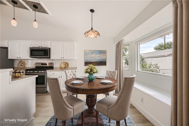 dining space featuring light wood-type flooring and vaulted ceiling