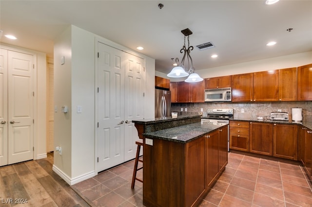 kitchen featuring stainless steel appliances, backsplash, pendant lighting, a kitchen breakfast bar, and a center island