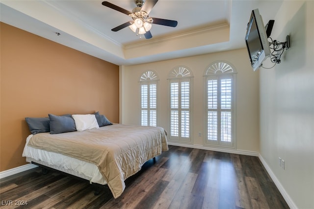 bedroom featuring dark hardwood / wood-style flooring, a raised ceiling, ceiling fan, and crown molding