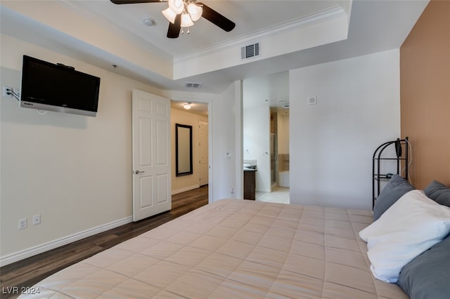 bedroom featuring crown molding, light wood-type flooring, a raised ceiling, ceiling fan, and ensuite bathroom