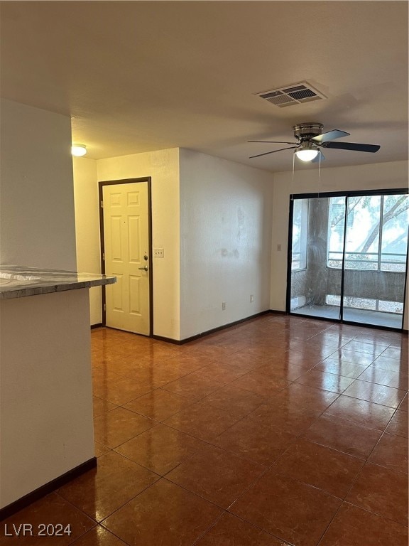 tiled empty room featuring ceiling fan