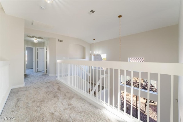 hall featuring light carpet and a chandelier