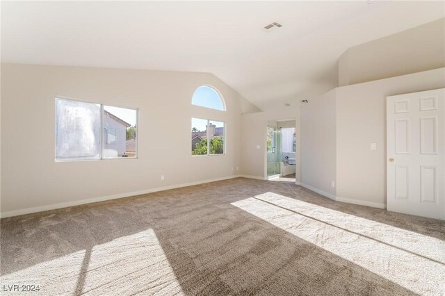 spare room featuring carpet flooring and lofted ceiling