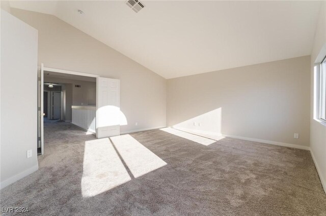 carpeted empty room featuring high vaulted ceiling