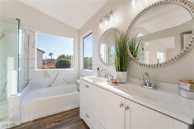 bathroom featuring a tub to relax in, hardwood / wood-style floors, vanity, and lofted ceiling