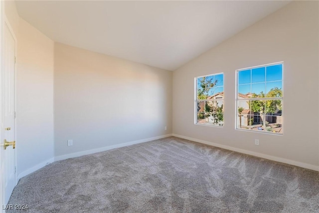 carpeted spare room featuring vaulted ceiling