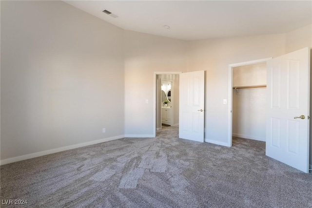 unfurnished bedroom featuring carpet, a closet, and vaulted ceiling