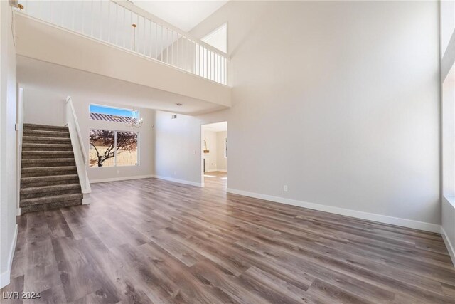 unfurnished living room featuring a towering ceiling and dark hardwood / wood-style floors