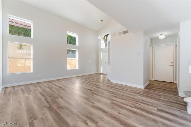 interior space with light hardwood / wood-style floors, high vaulted ceiling, and an inviting chandelier