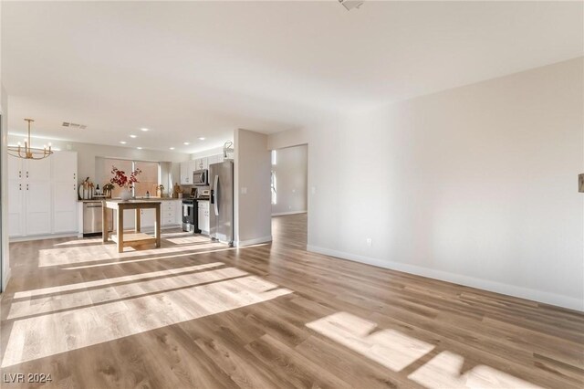 unfurnished living room with light hardwood / wood-style floors and a chandelier