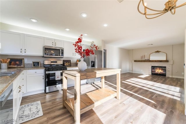 kitchen with white cabinetry, stainless steel appliances, a notable chandelier, and wood-type flooring