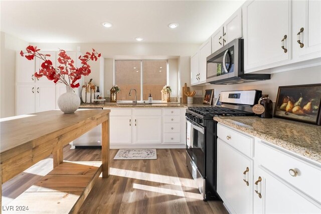 kitchen featuring hardwood / wood-style floors, sink, light stone counters, white cabinetry, and stainless steel appliances