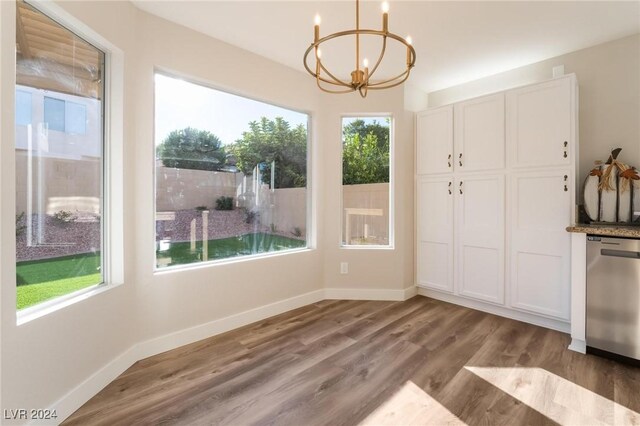 unfurnished dining area with hardwood / wood-style flooring, a healthy amount of sunlight, and an inviting chandelier