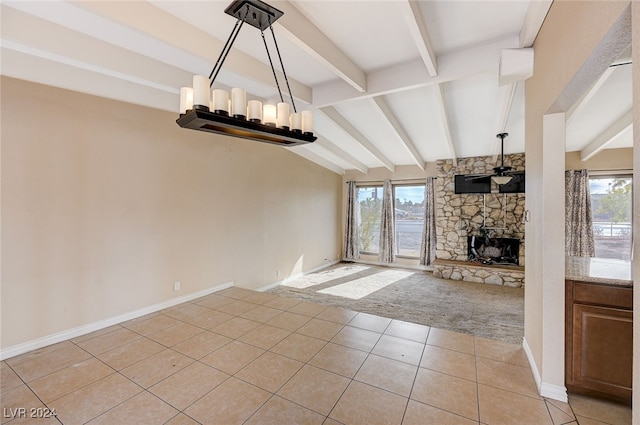 unfurnished living room featuring a fireplace, light tile patterned floors, vaulted ceiling with beams, and a healthy amount of sunlight