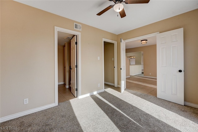 unfurnished bedroom featuring ceiling fan, light colored carpet, and connected bathroom