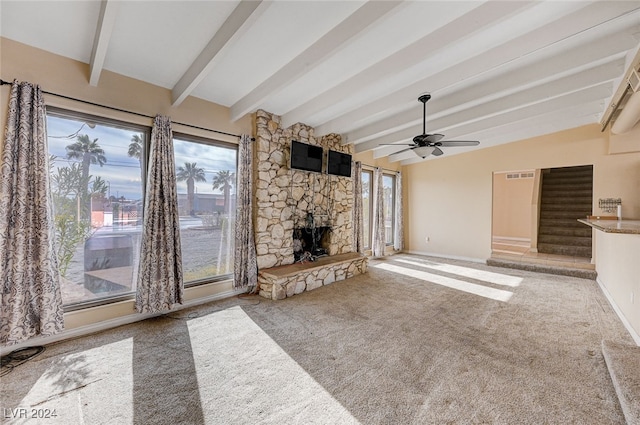 unfurnished living room featuring beamed ceiling, light colored carpet, a fireplace, and ceiling fan