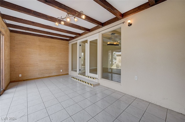 interior space with beam ceiling, an inviting chandelier, and wood walls