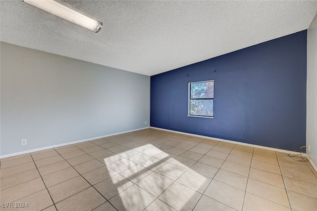 empty room featuring light tile patterned floors, a textured ceiling, and vaulted ceiling