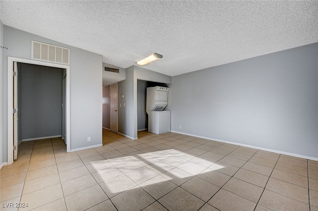 unfurnished bedroom with light tile patterned floors, a textured ceiling, and stacked washer and dryer