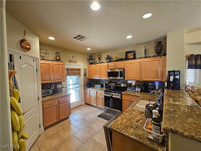 kitchen featuring tasteful backsplash, stainless steel appliances, light tile patterned floors, sink, and kitchen peninsula