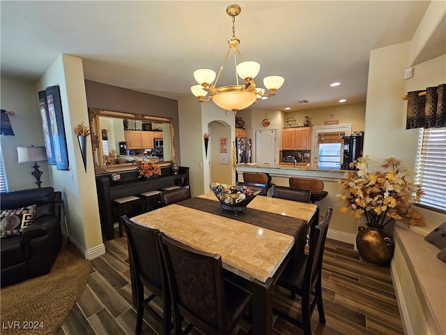 dining room featuring a healthy amount of sunlight, dark hardwood / wood-style floors, and an inviting chandelier