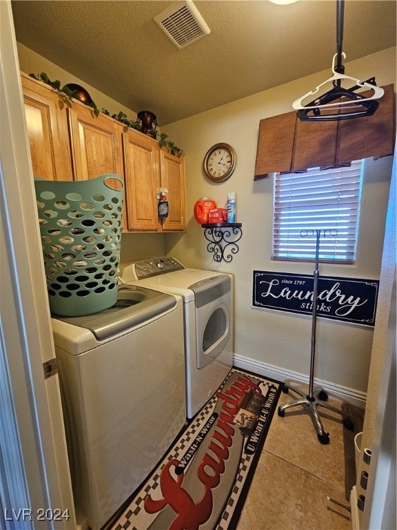 laundry area featuring cabinets, a textured ceiling, washer and clothes dryer, and tile patterned floors