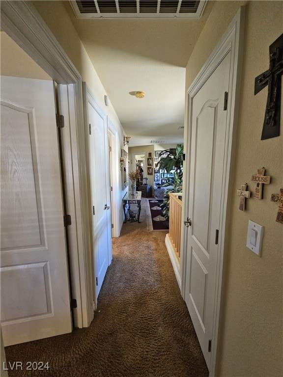 hall featuring dark colored carpet