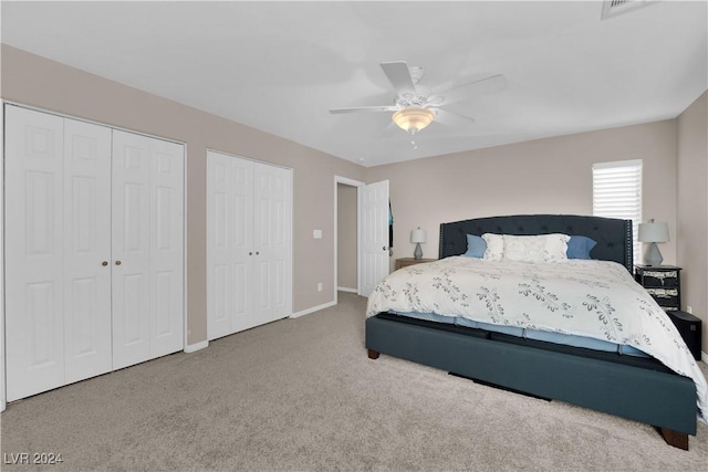 bedroom with ceiling fan, carpet floors, and two closets