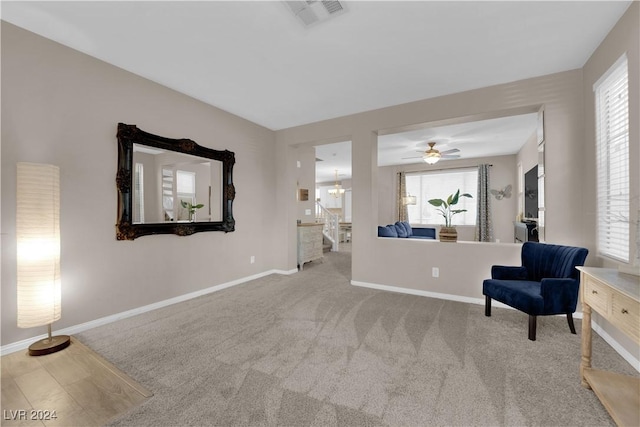 living area with ceiling fan with notable chandelier and carpet floors